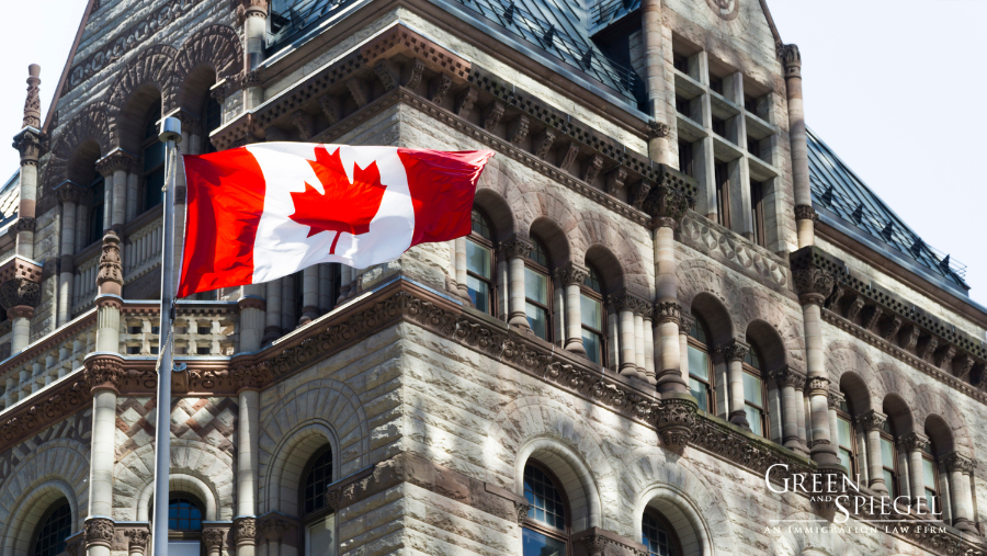 Canada flag in front of building - 5 Key Takeaways from Canada’s Plan to Improve Immigration System