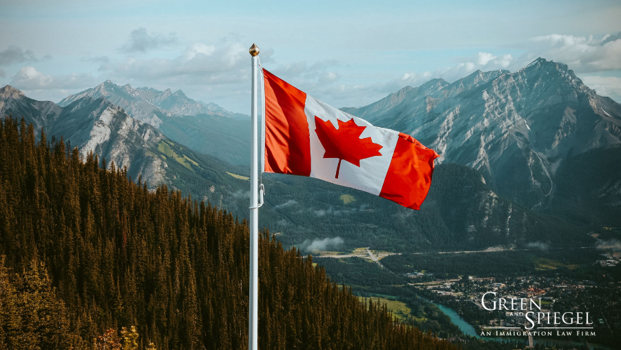 Canadian flag in front of mountain range. 